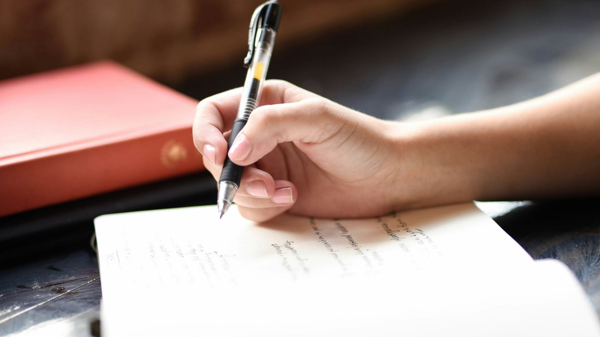 a person writing on a piece of paper with a pen