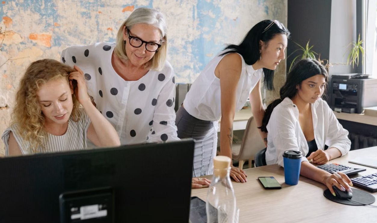 A group of women collaborating in a contemporary office setting, engaging in teamwork and discussion.
