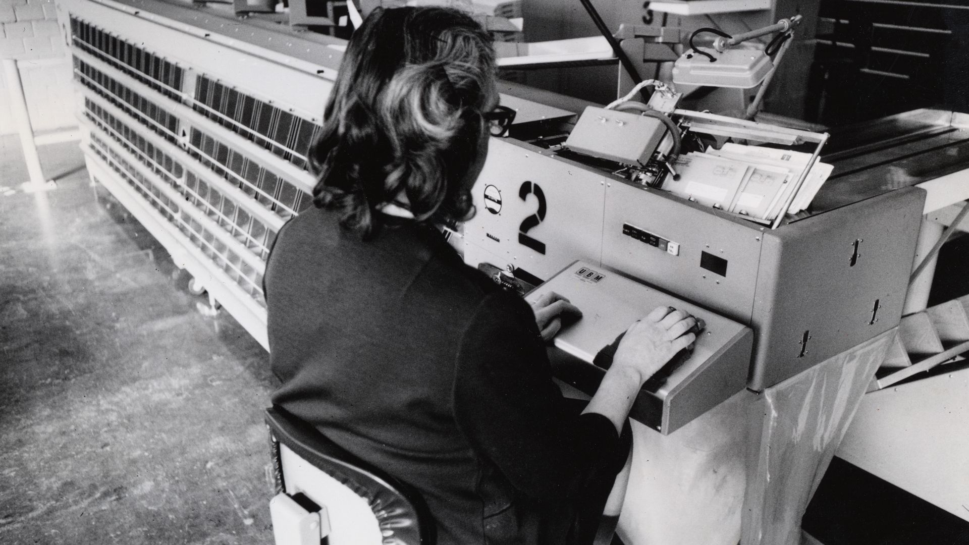 Description: This is an image of a postal employee working at a mechanized machine that sorts envelopes based on ZIP code.
Creator/Photographer: Unidentified photographer
Medium: Black and white photographic print
Geography: USA
Date: 1965
Collection: U.S
