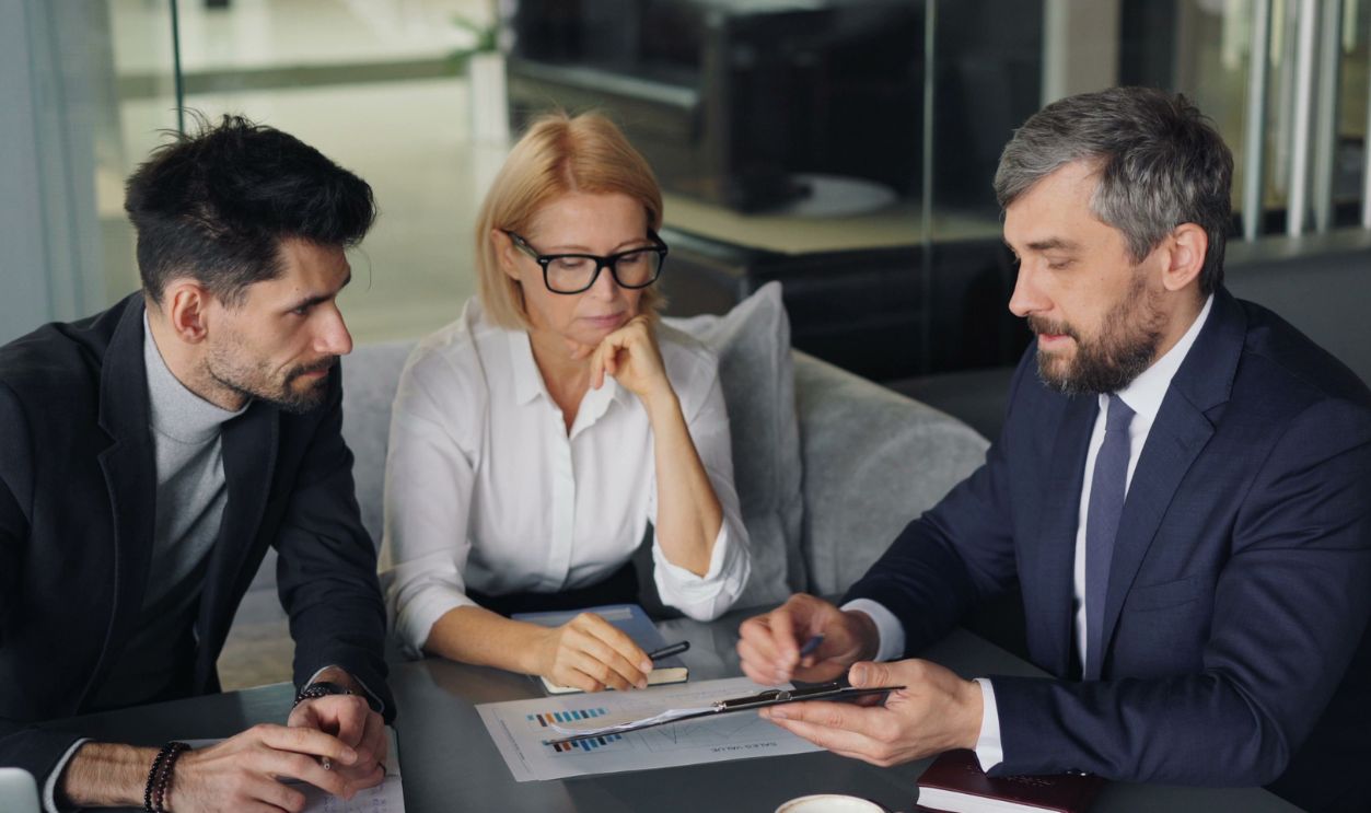 Three professionals engaged in a business discussion at an office table 