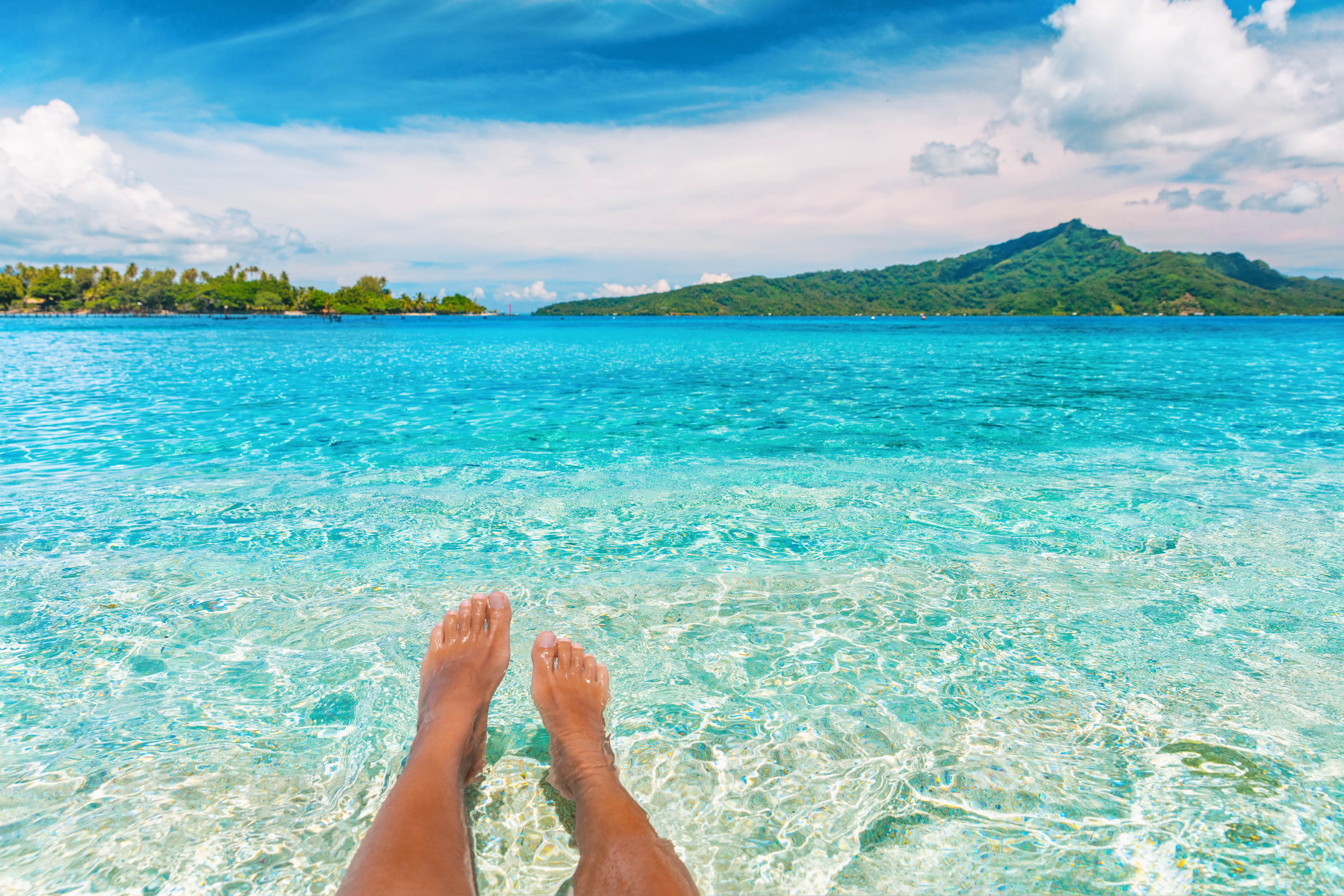 A person's feet in the water at Bora Bora, French Polynesia