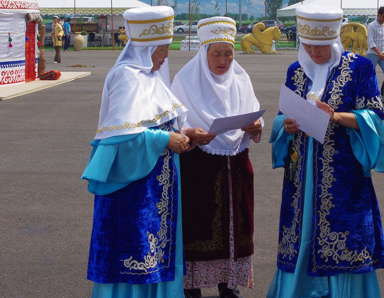Three matrons in traditional Kazakh dress take a break from creating intricate weavings to decorate yurts. - 2012