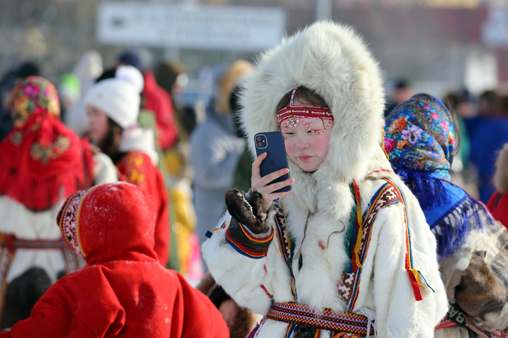 Nenets reindeer herder girl in fur clothes talks on the phone