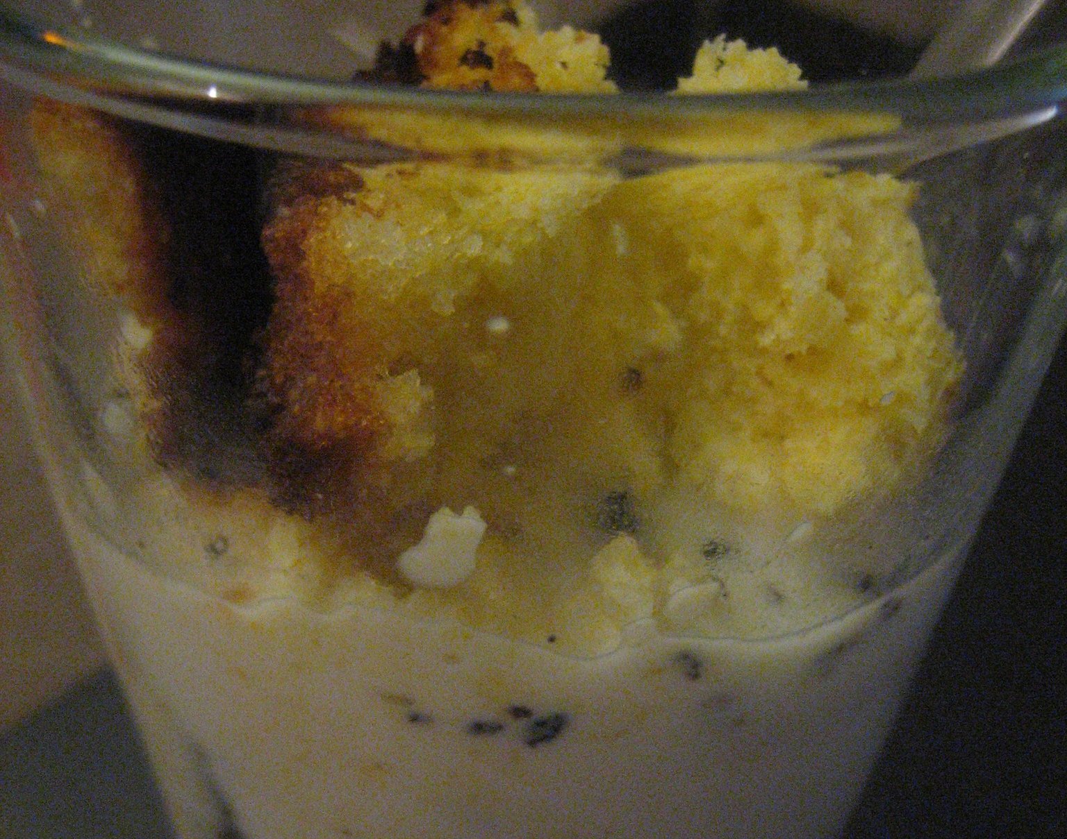 Close-up Photo of a drinking glass filled up with milk  and crumbled cornbread