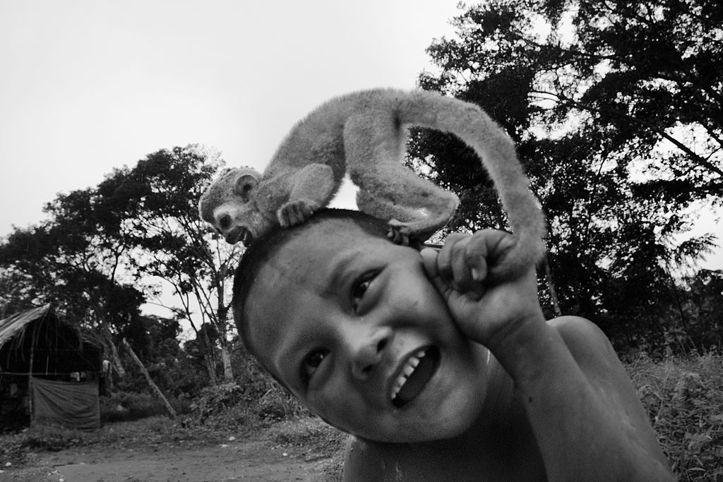 Nukak boy plays with a baby monkey