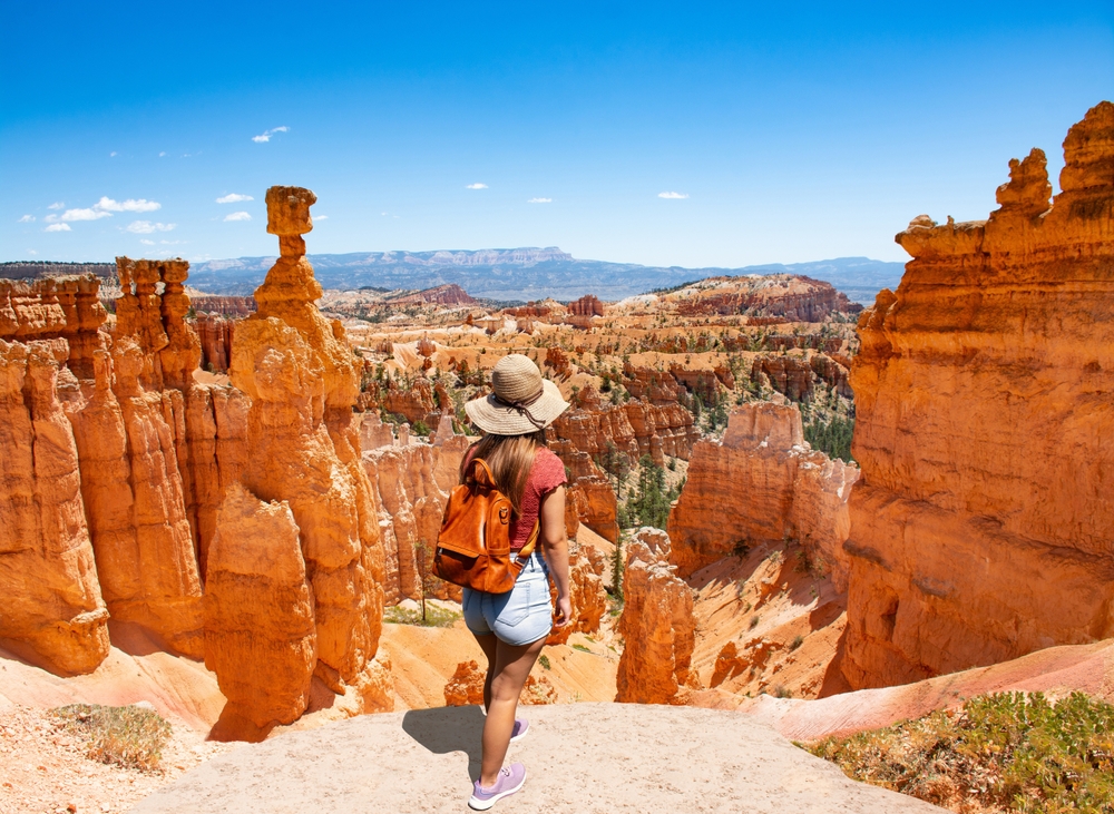 Woman standing next to Thor's Hammer hoodoo on top of mountain looking at beautiful view. Bryce Canyon National Park.