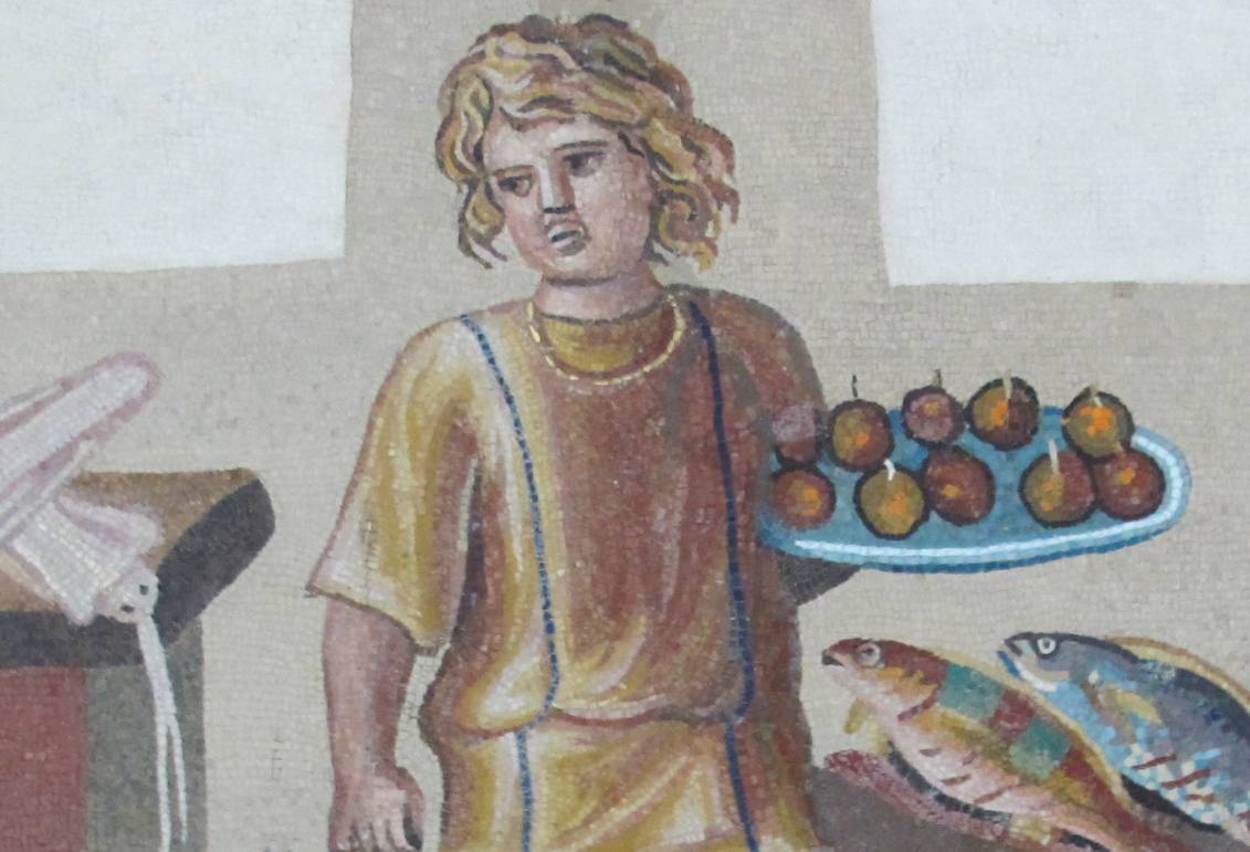 A boy holding a platter of fruits and what may be a bucket of crabs