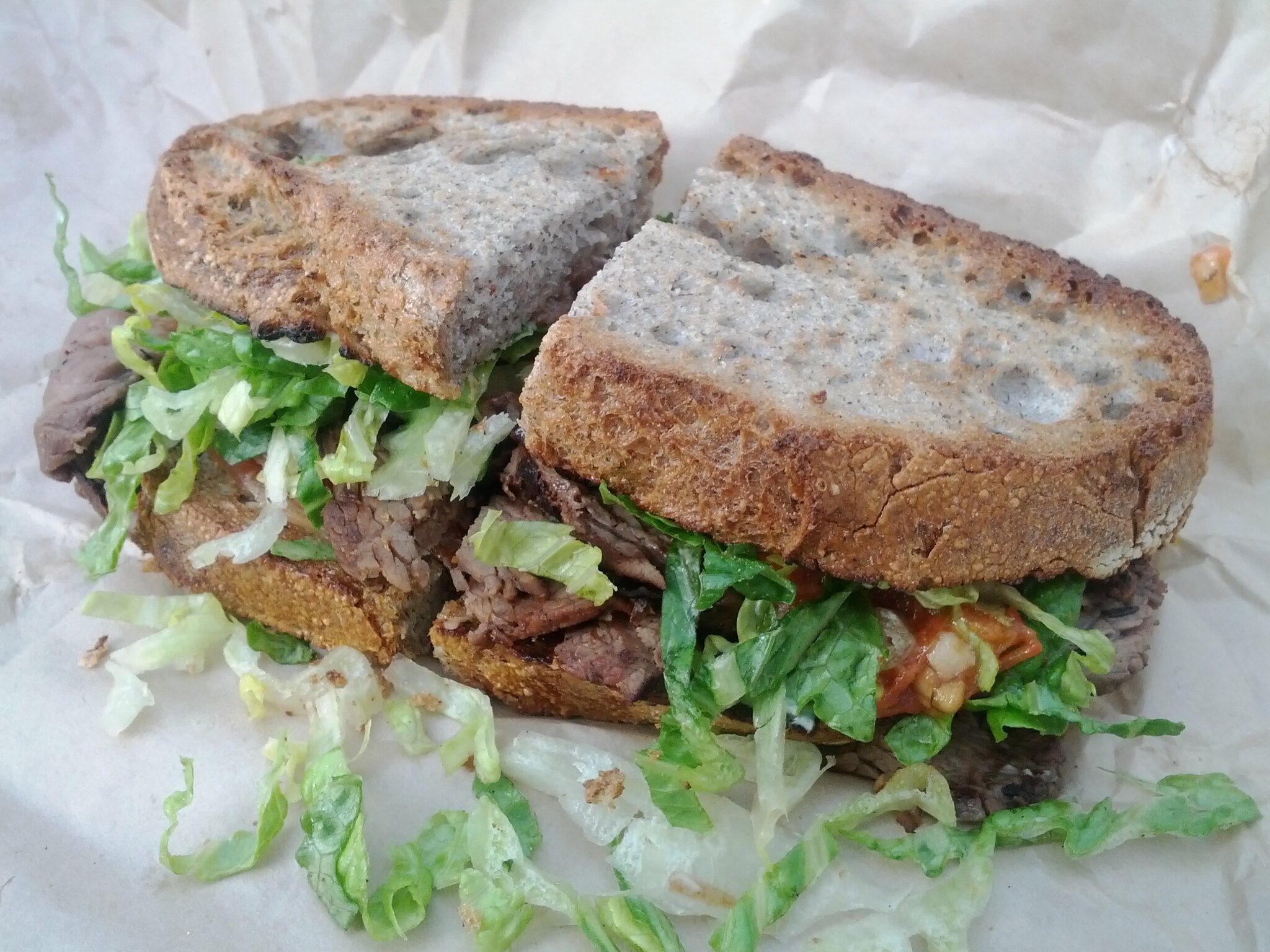 A Steak BLT wrapped in white paper