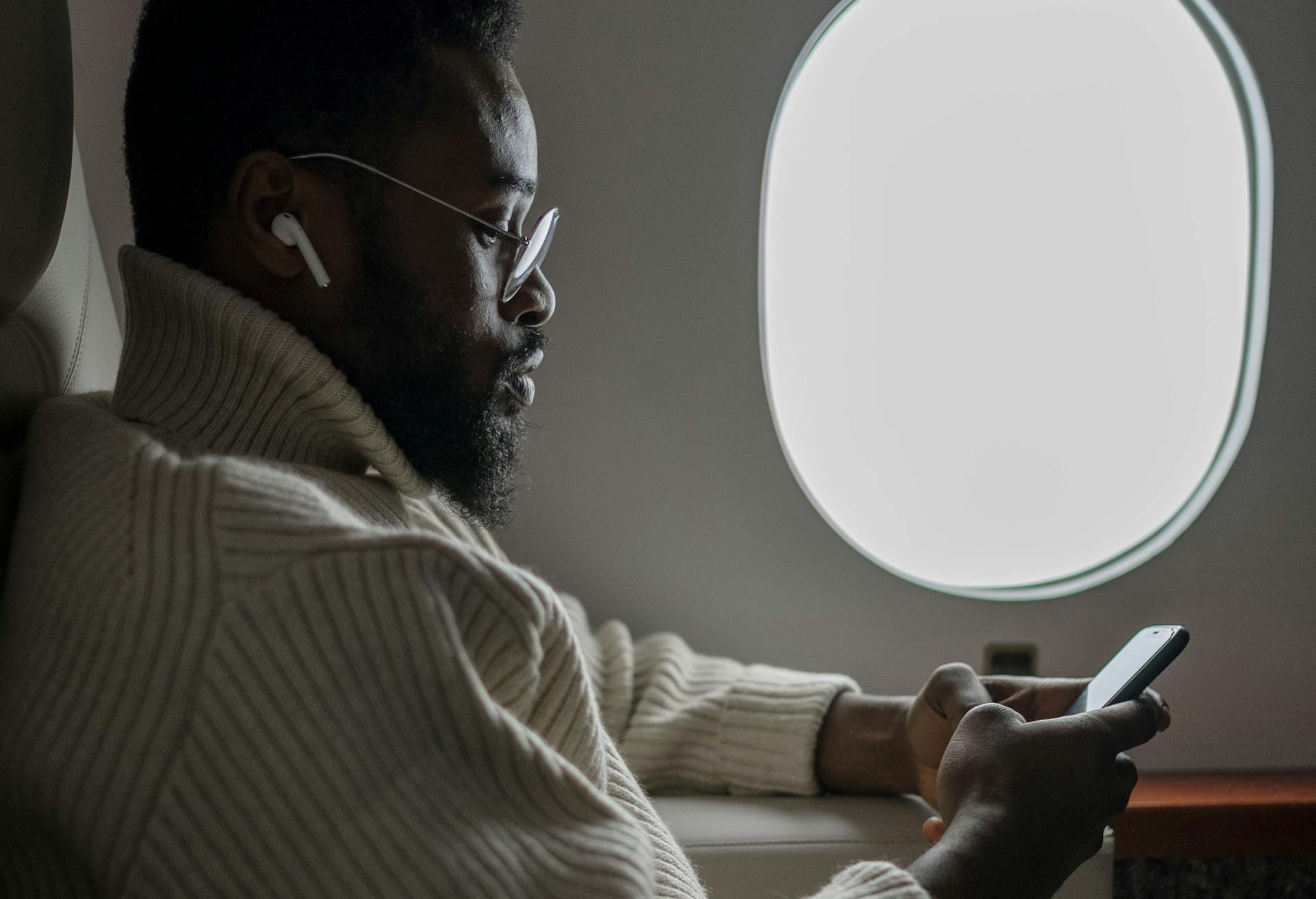 A Man in Beige Sweater Sitting Beside Window Plane