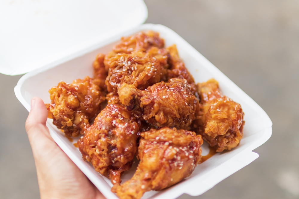Hand holding deep fried chicken wings with
