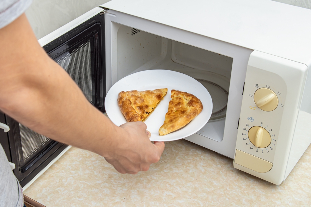 Man puts pies to warm up in the microwave oven