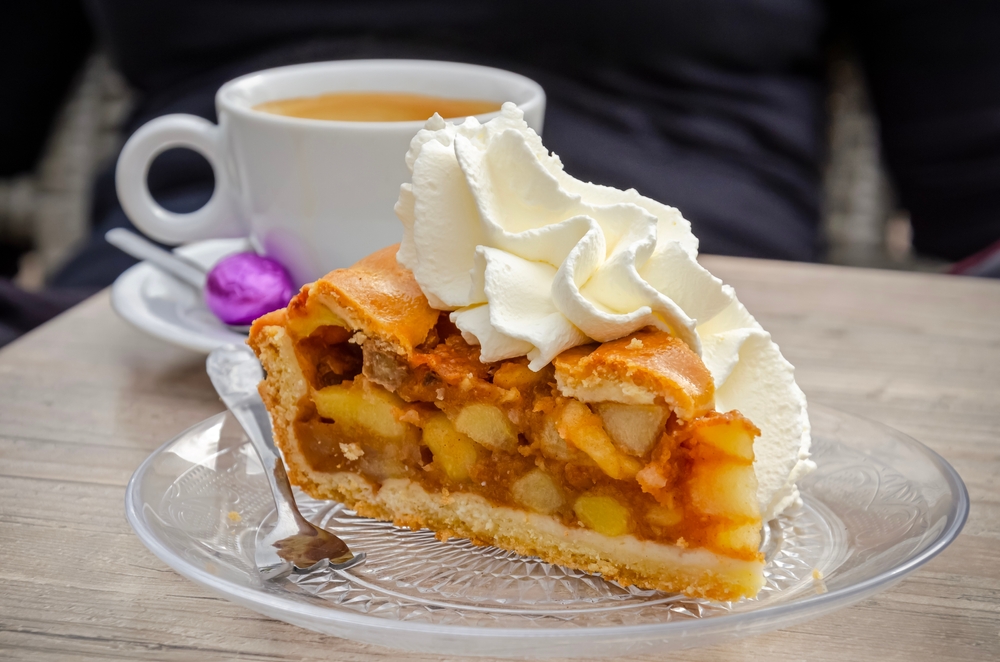 Apple pie with whipped cream on a glass plate