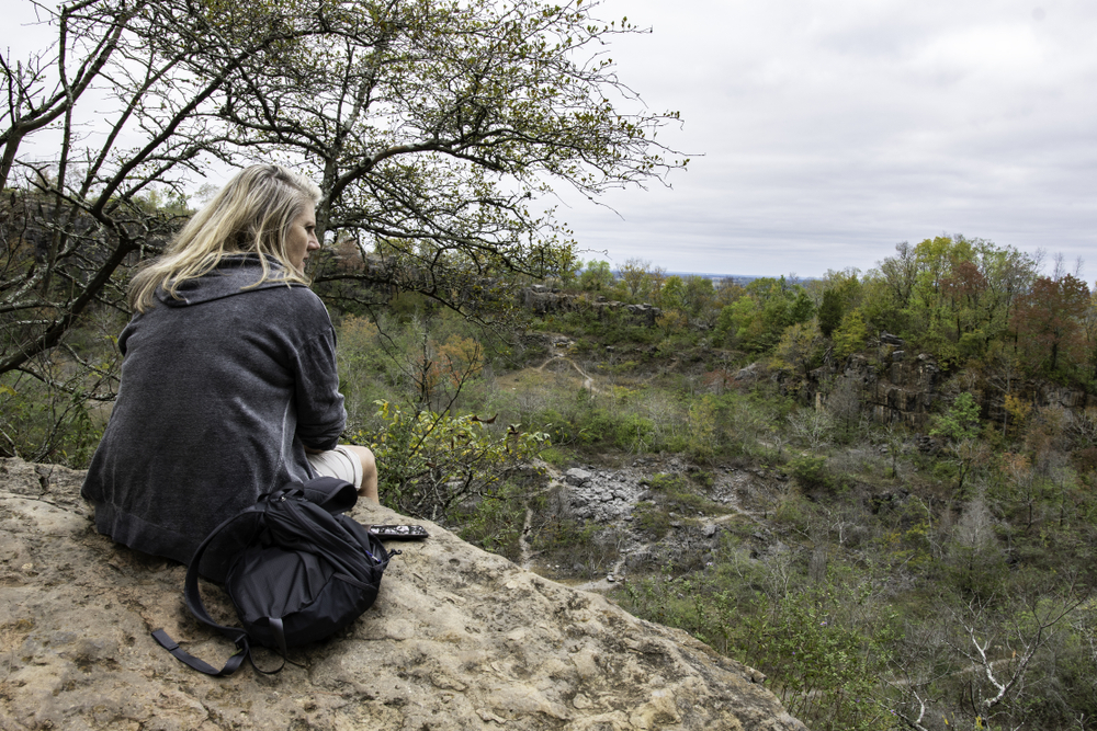 Female hiker sits on the edge of an overlook of the rock quarry at Ruffner Mountain Nature Preserve