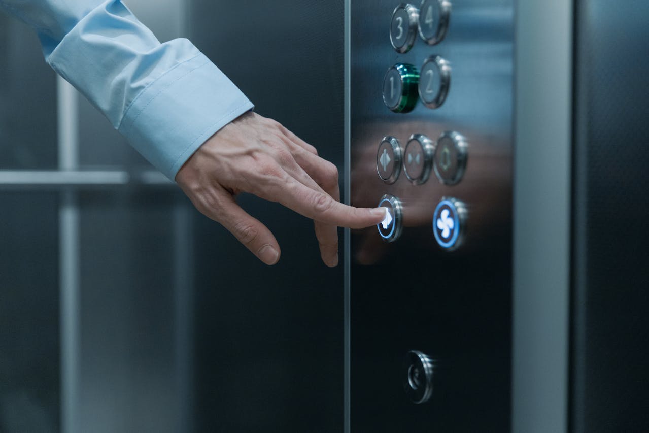 A hand pressing an elevator button