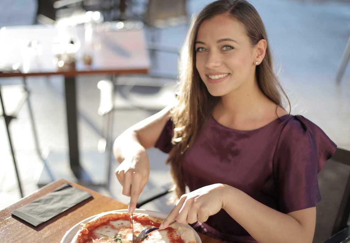 Young Woman in Purple Top Eating Pizza