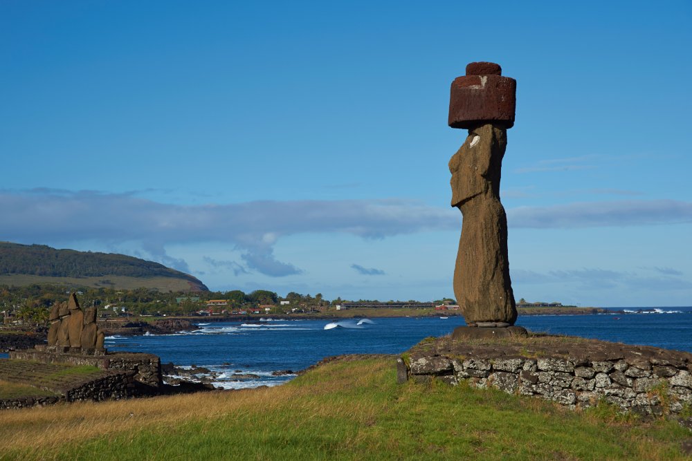 A single moai statue stands tall on a grassy hill overlooking the ocean on Easter Island (Rapa Nui)