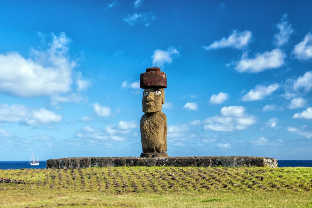 A single moai statue stands tall on a grassy hill overlooking the ocean on Easter Island (Rapa Nui)