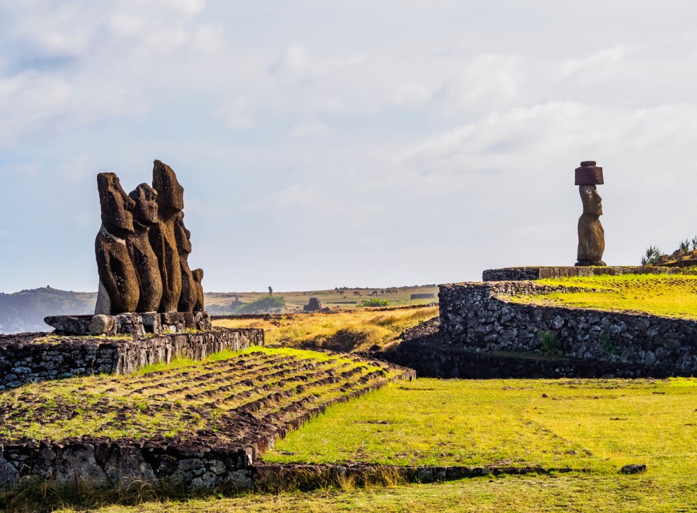 A line of majestic moai statues stand tall on Easter Island, overlooking a vast expanse of green grassland