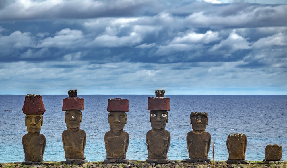 A line of moai statues stand tall on a grassy field on Easter Island (Rapa Nui)