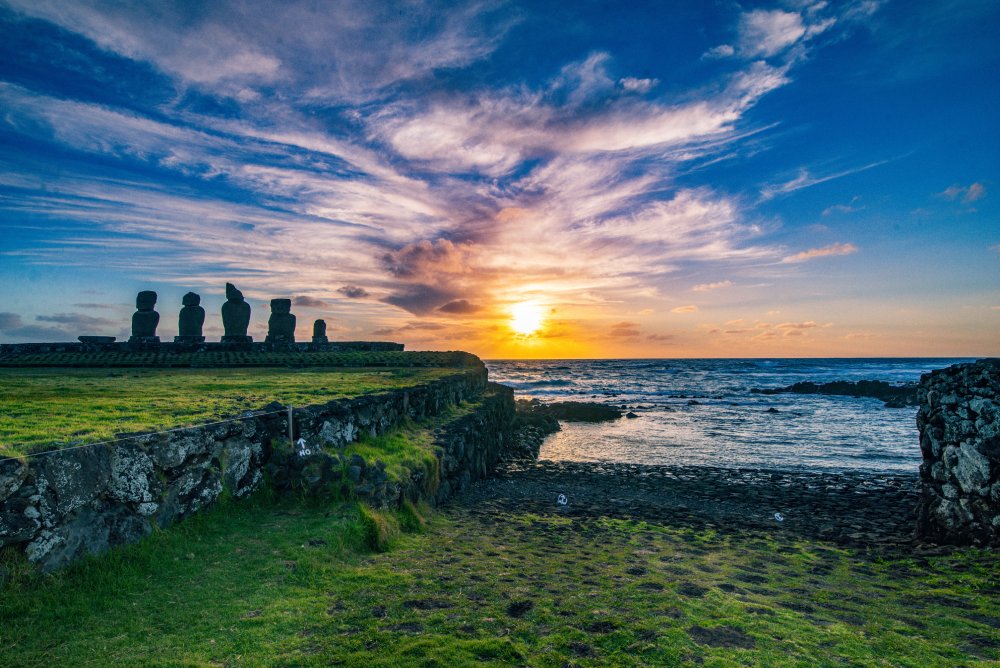 Easter Island, with a line of moai statues silhouetted against the vibrant sky