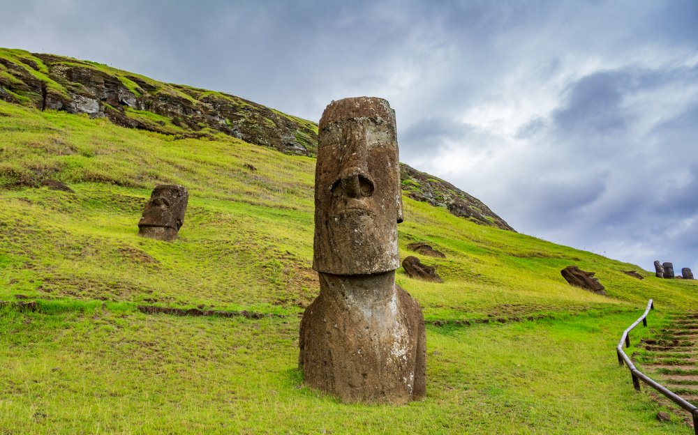 A group of moai statues stand partially buried in a grassy field on Easter Island (Rapa Nui)