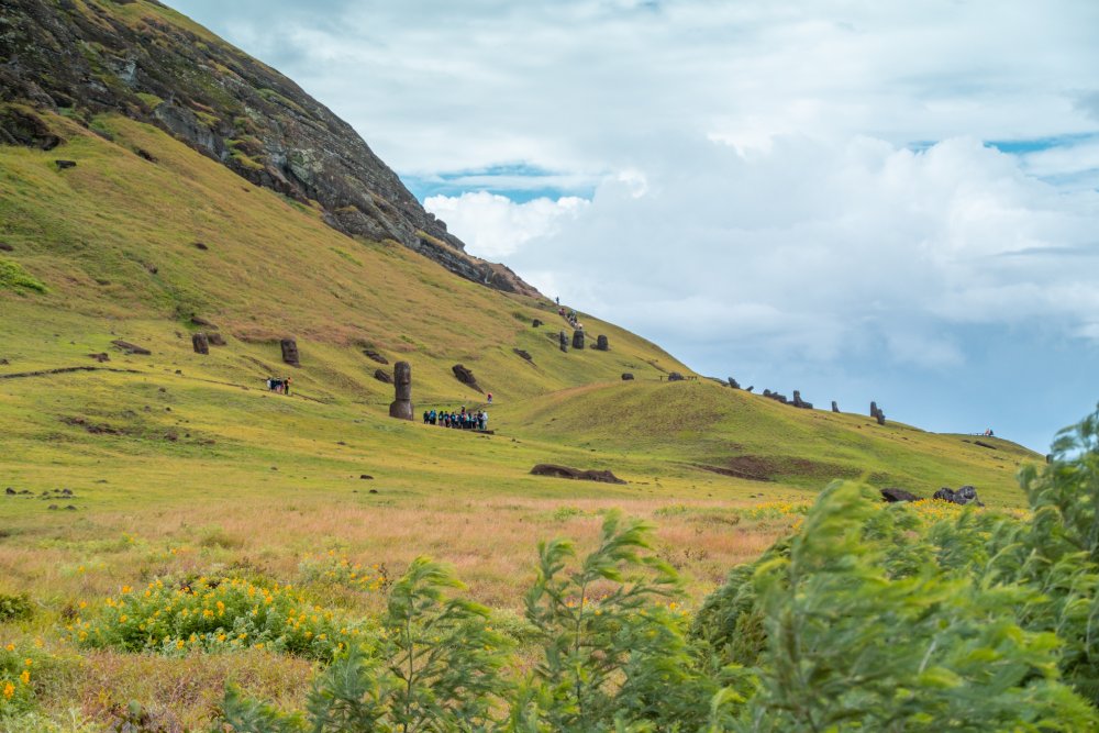 Iconic moai statues of Easter Island, set against a backdrop of rolling hills and a cloudy sky