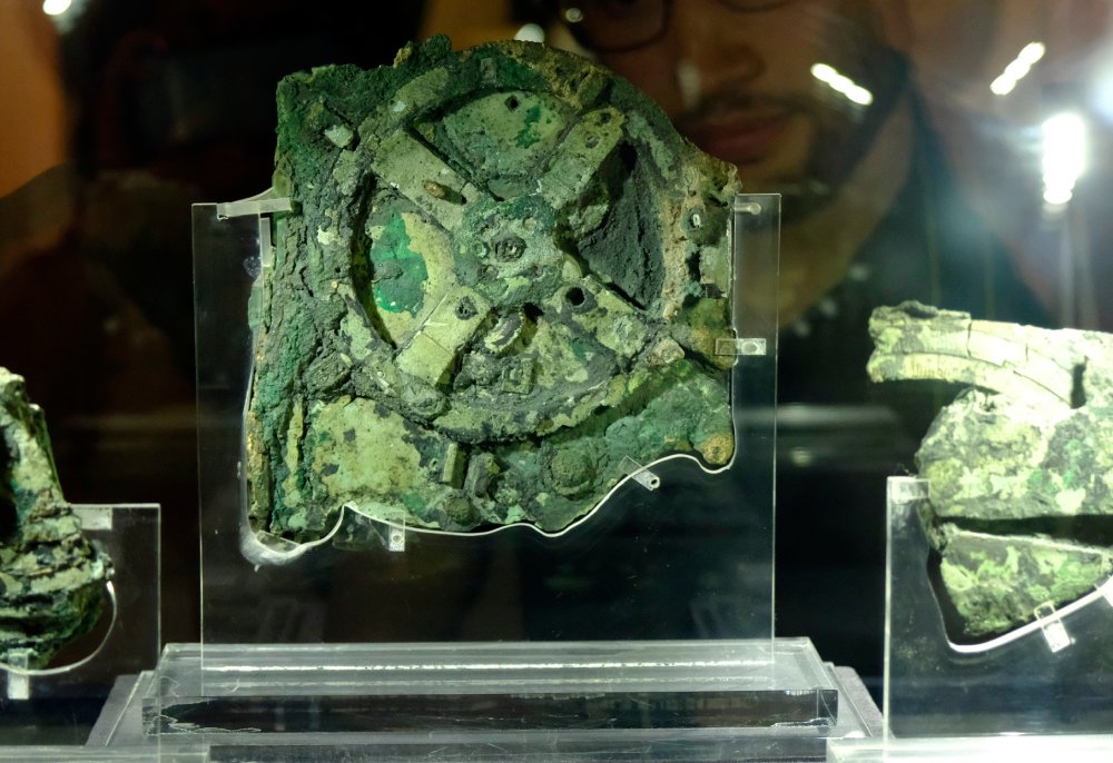Visitors look at a fragment of the 2,100-year-old Antikythera Mechanism