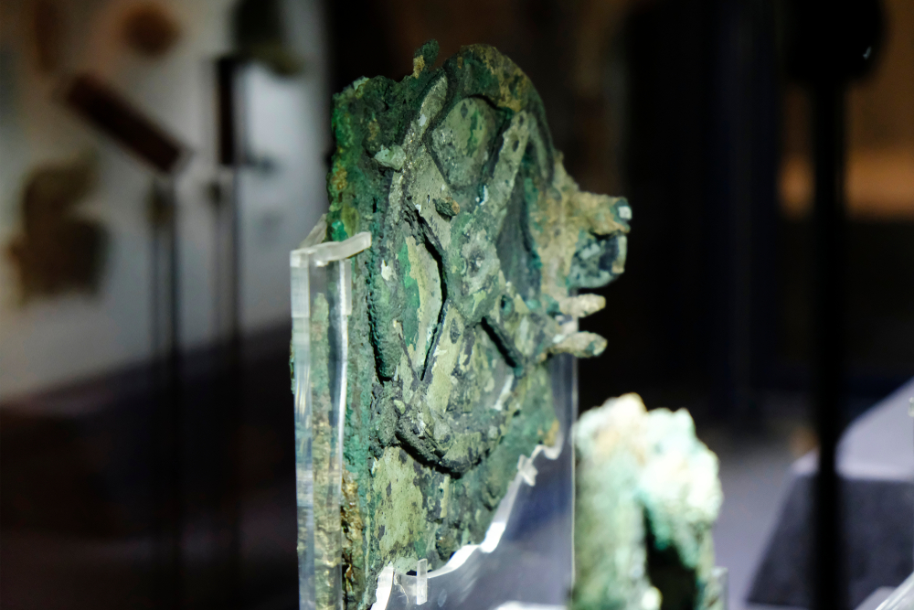 Visitors look at a fragment of the 2,100-year-old Antikythera Mechanism