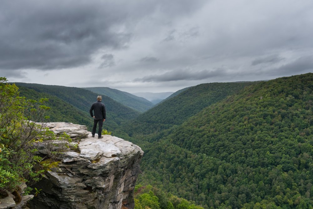Hiker reaching the edge of a cliff at Lindy Point Overlook in West Virginia