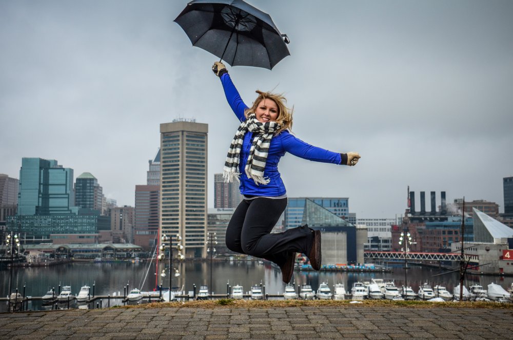 Woman jumps with an umbrella in Baltimore at Federal Hill Park