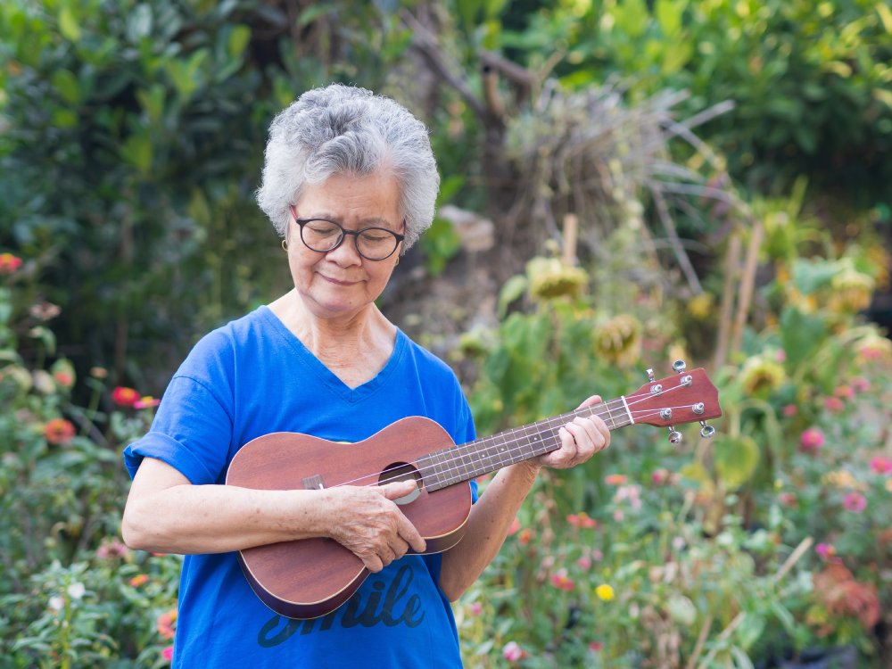Portrait of elderly woman playing ukulele in her garden