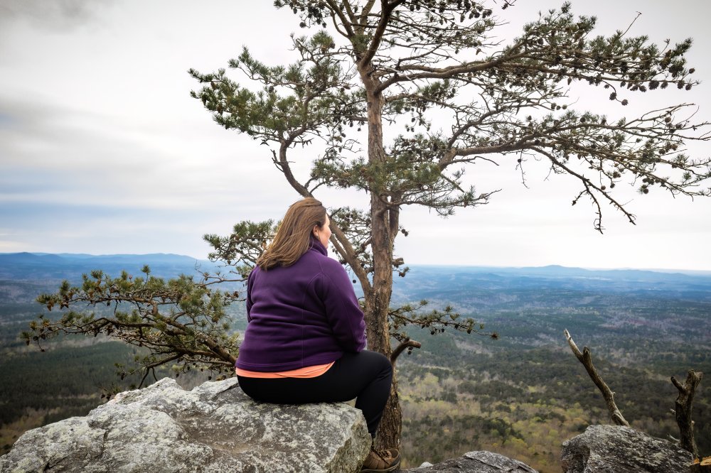 Woman sitting on cliff edge at Cheaha State Park Mountain in Alabama