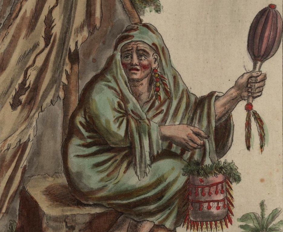 Native American priest, shaman, or medicine man sits outside a shelter.