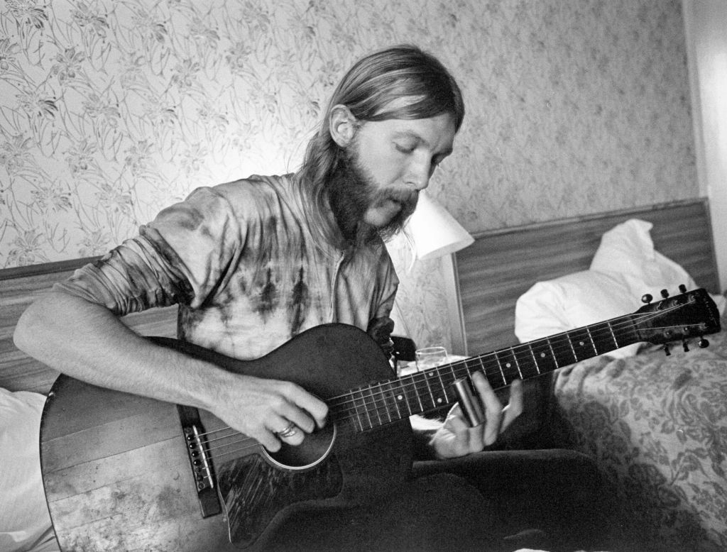 Guitarist Duane Allman playing a guitar in hotel room