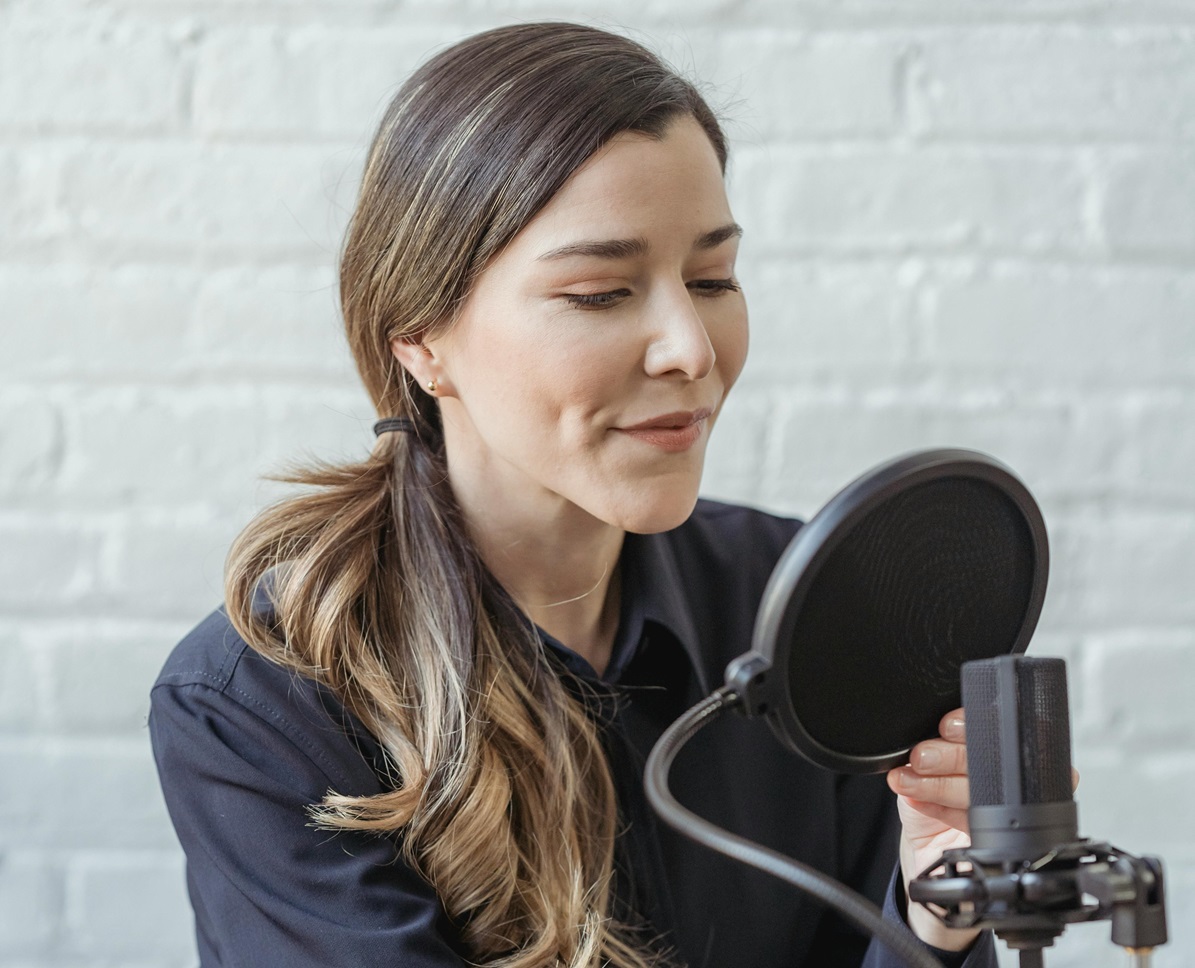 Smiling woman recording voice on microphone