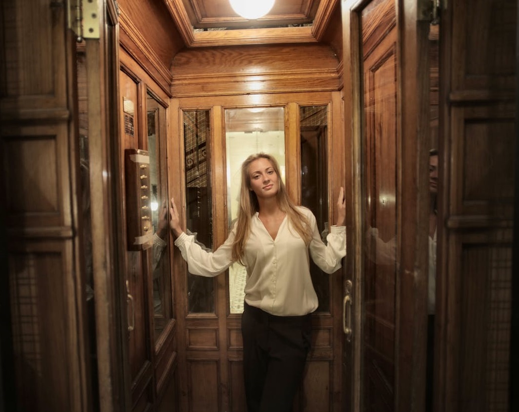 Woman in White Long Sleeve Shirt at elevator.