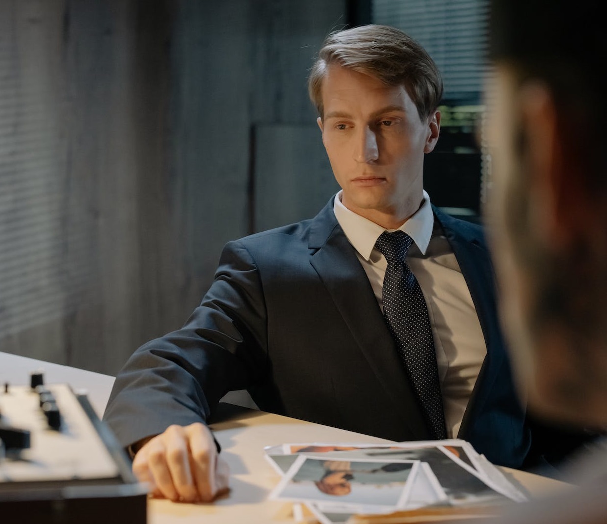 Man in suit is talking with other person at office.