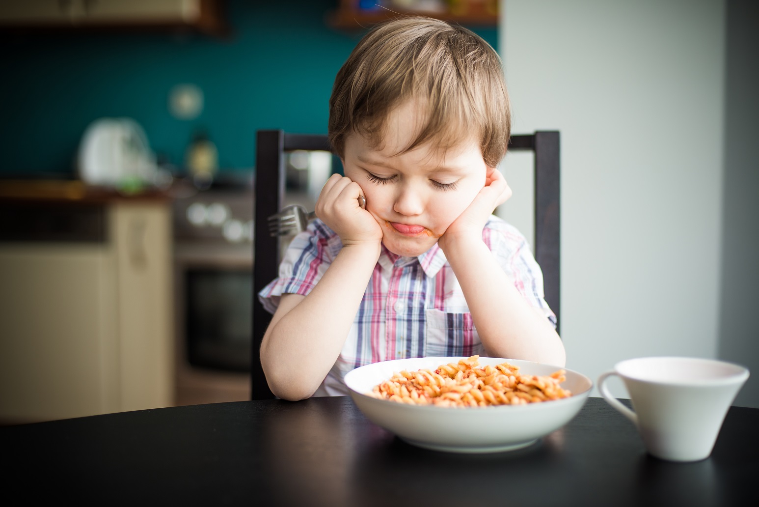 Offended little boy during eating spaghetti at dinner