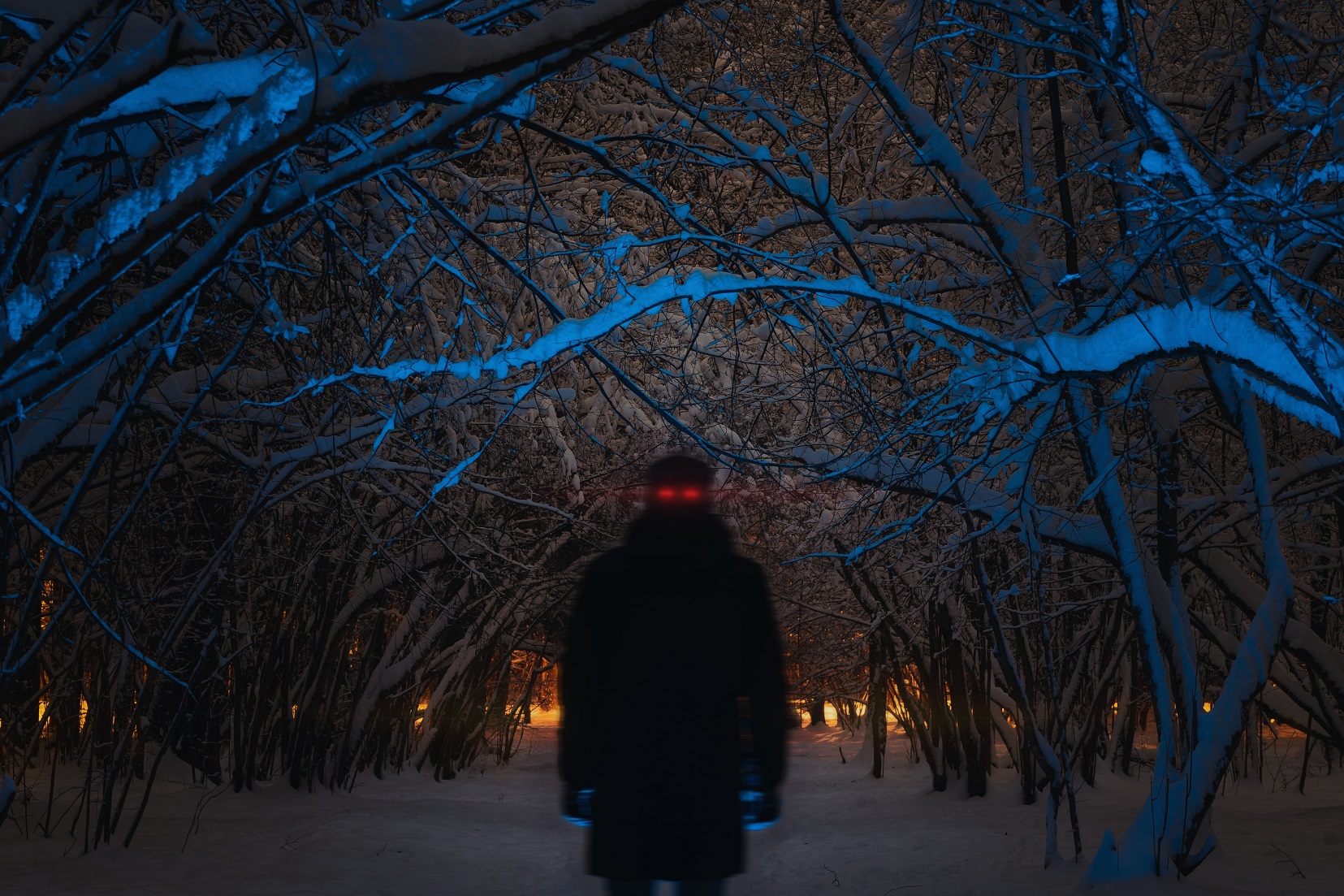 Human person with red glowing eyes in a dark night forest in winter.