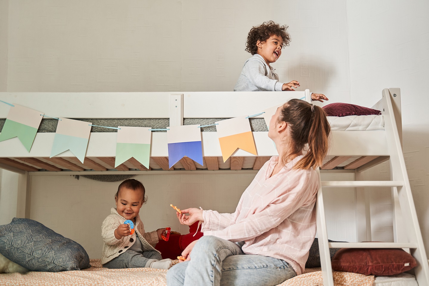 Mom looking at her cute laughing baby, while sitting at the cozy bunk bed