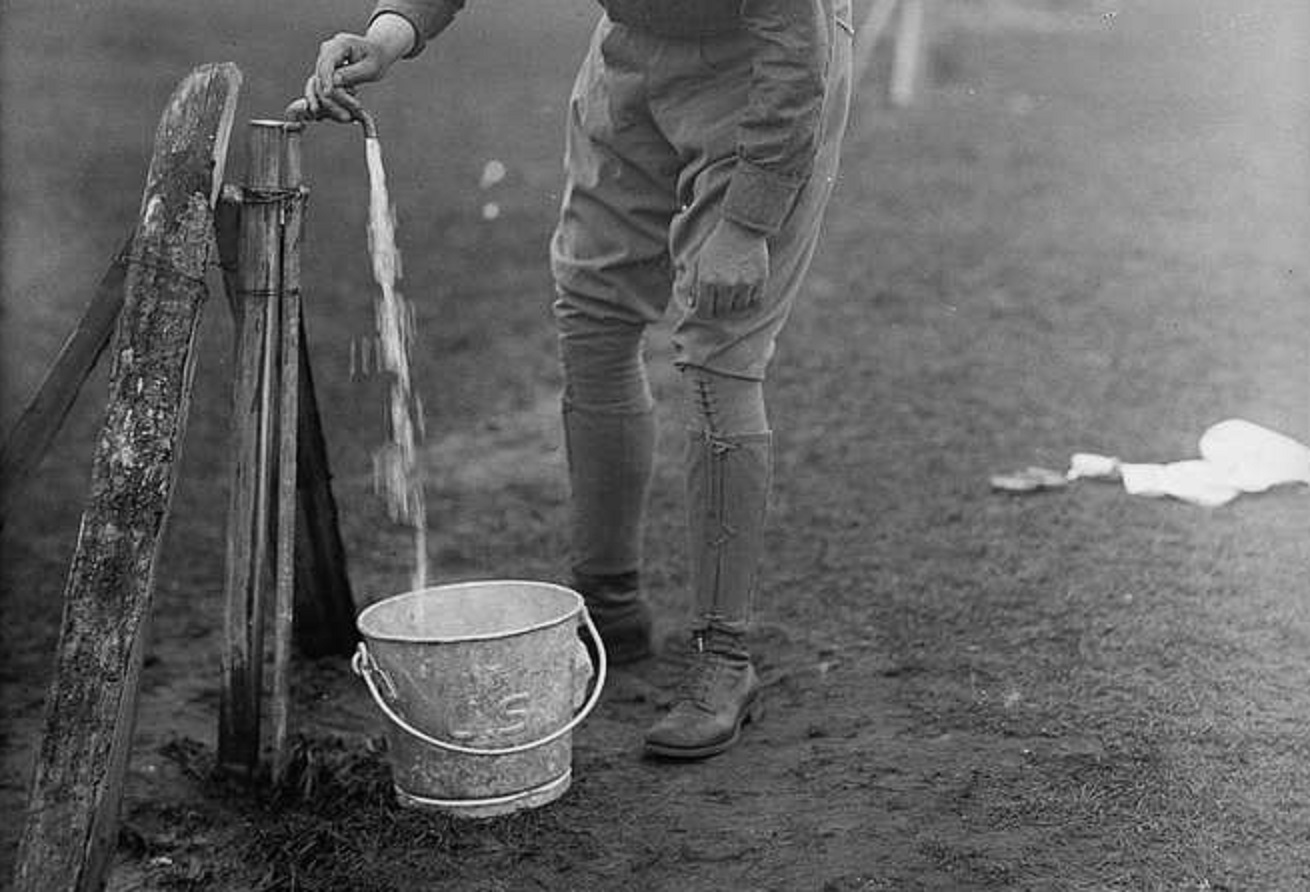Man filling a bucket with water - 1900s