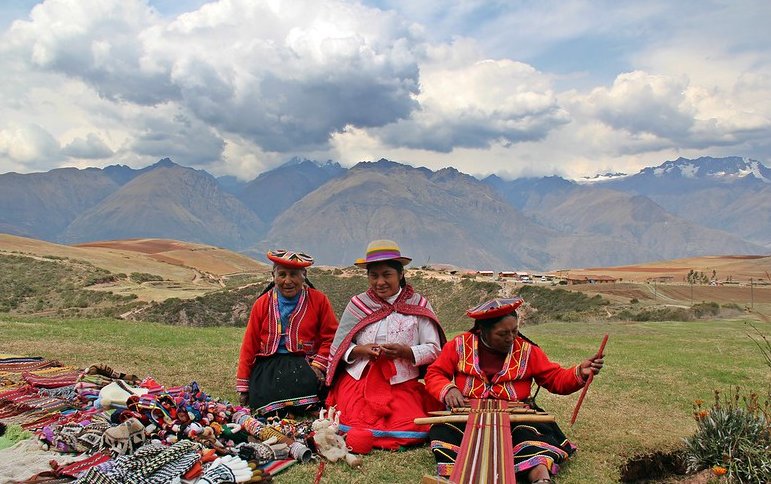 Quechua women in national costumes sitting and working on the ground