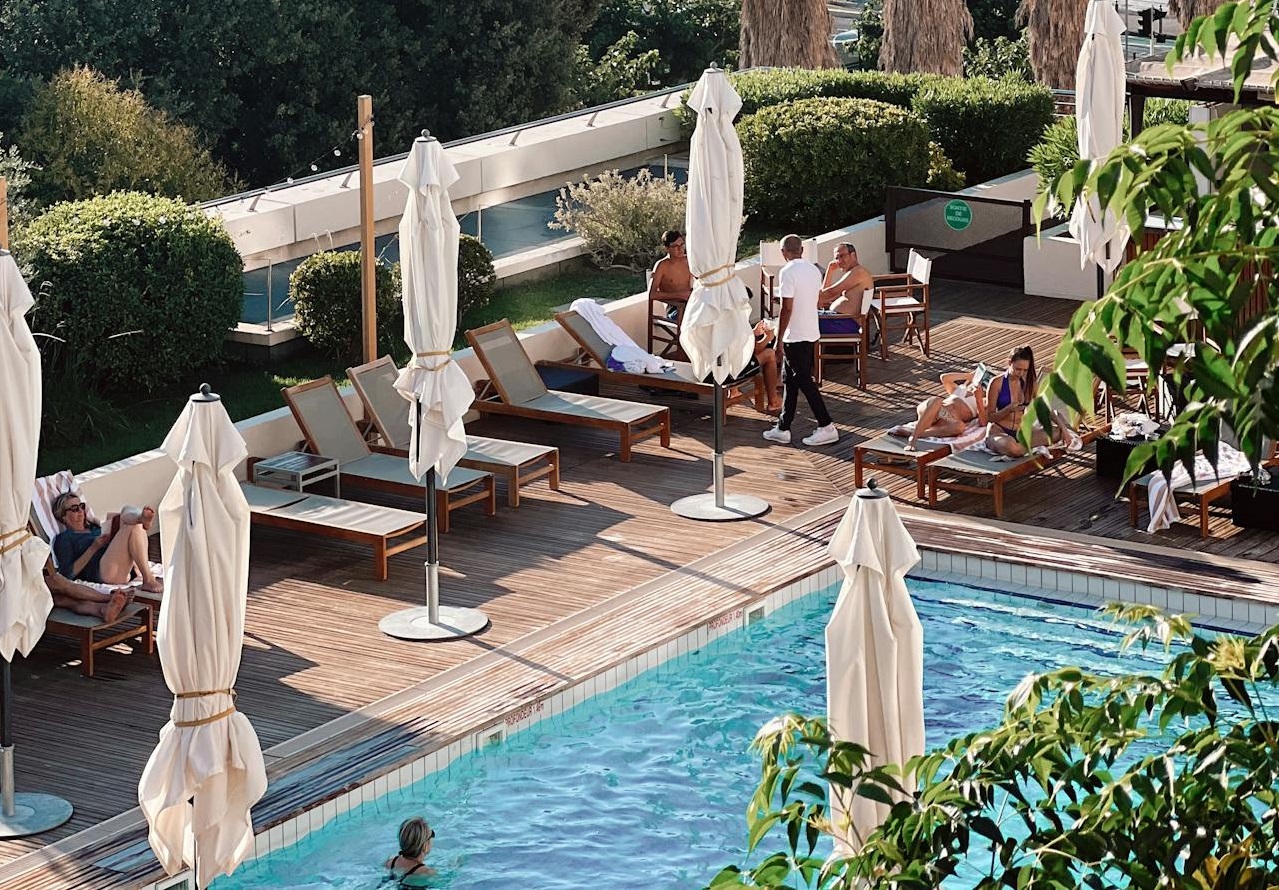 People on deckchairs by swimming pool.