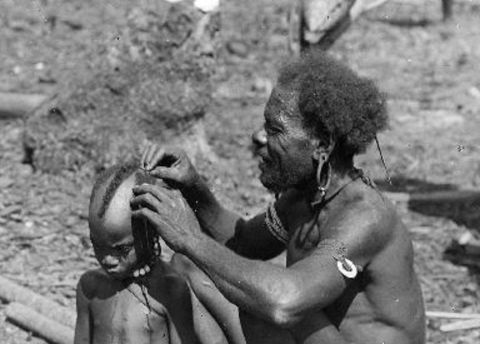 A Man in tribe Is Cutting A Boy's Hair With A Bamboo Knife - 1903