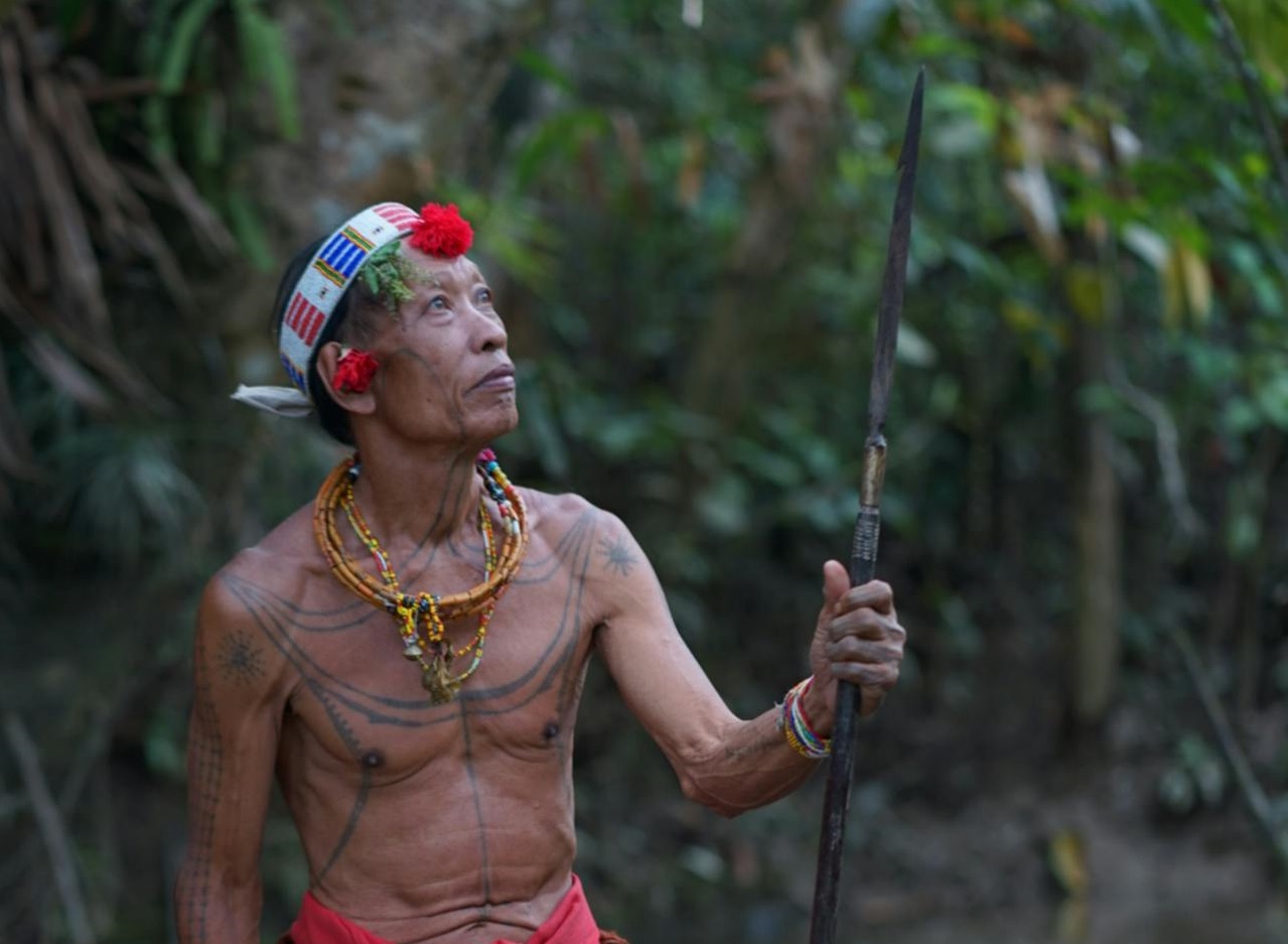 Man with traditional tattoos is holding a spear.