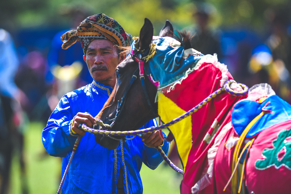 Bajau samah in traditional costume riding a decorated horse