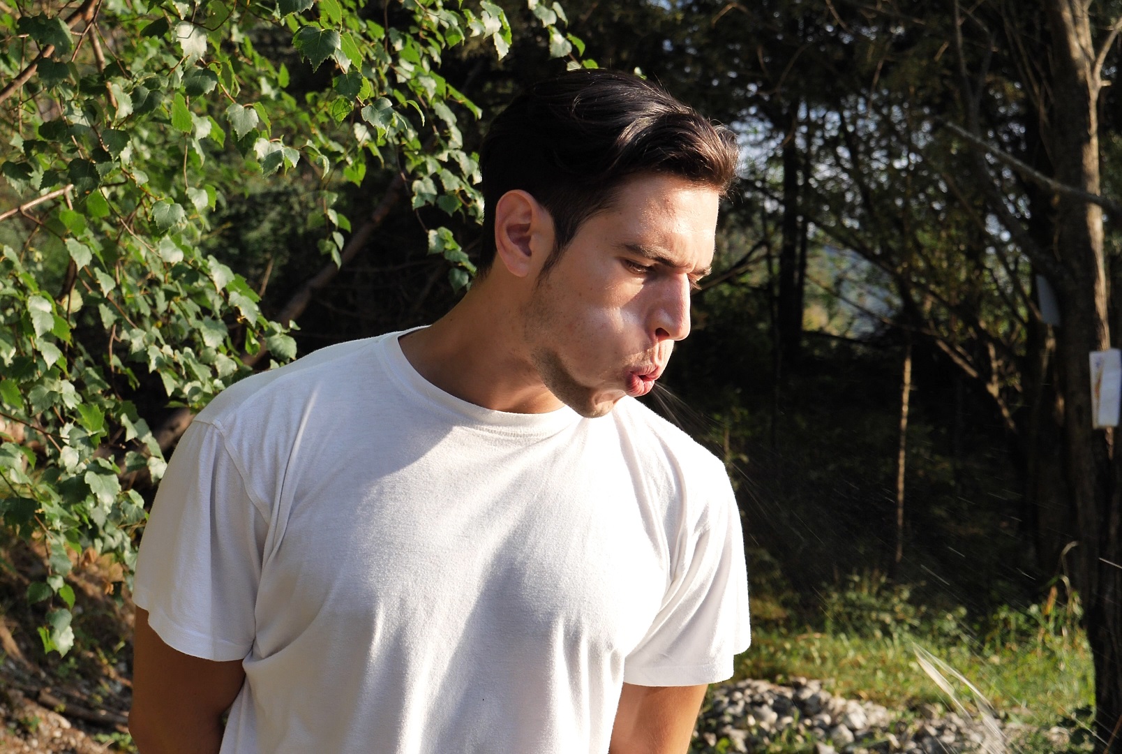 Young rude handsome man standing in nature, spitting on the ground