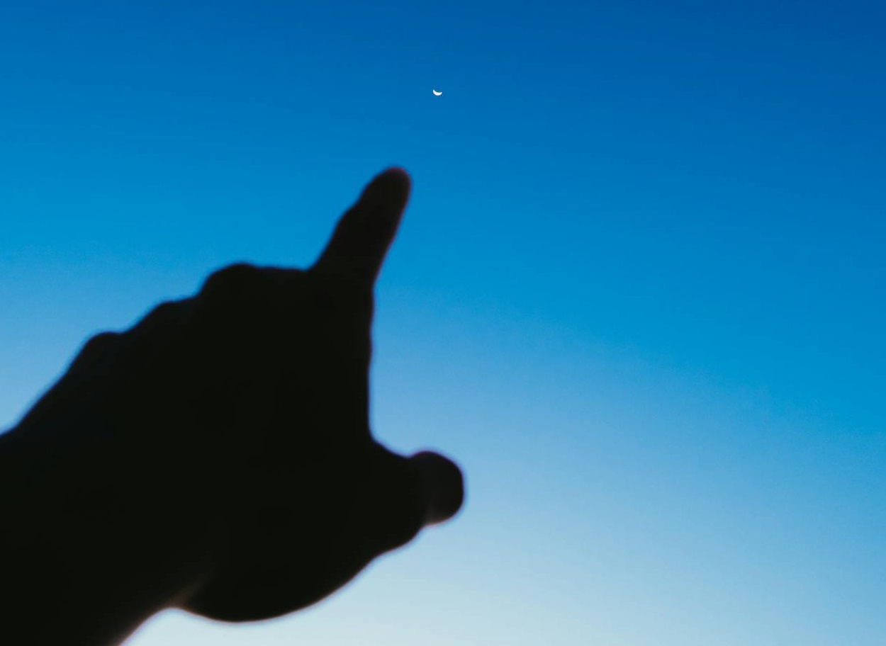 Crop hand pointing to the sky.