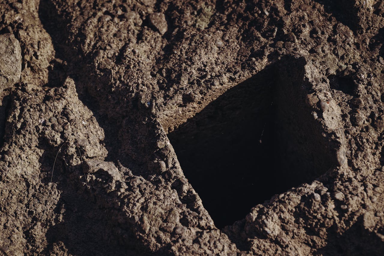 Rectangular hole dug in soil.