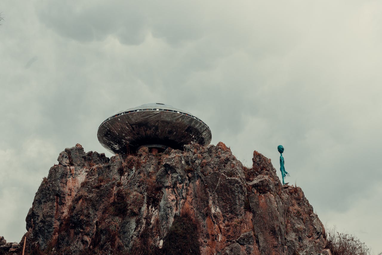UFO and an alien on a rock outside.